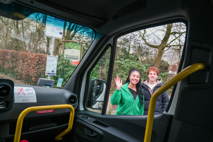 foto vanuit bus, twee reizigers zwaaien naar chauffeur